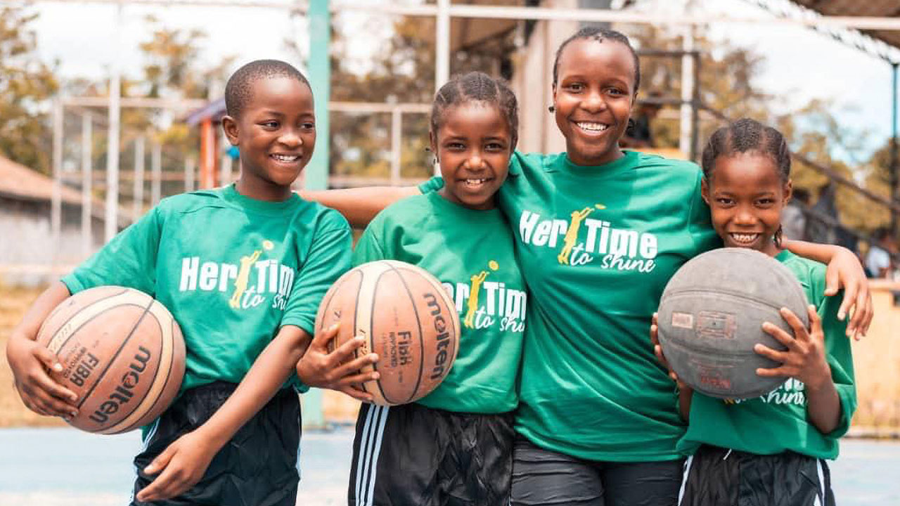 Die Mädchen des Basketballprojekts posieren für ein Gruppenfoto mit Basketbällen im Arm.