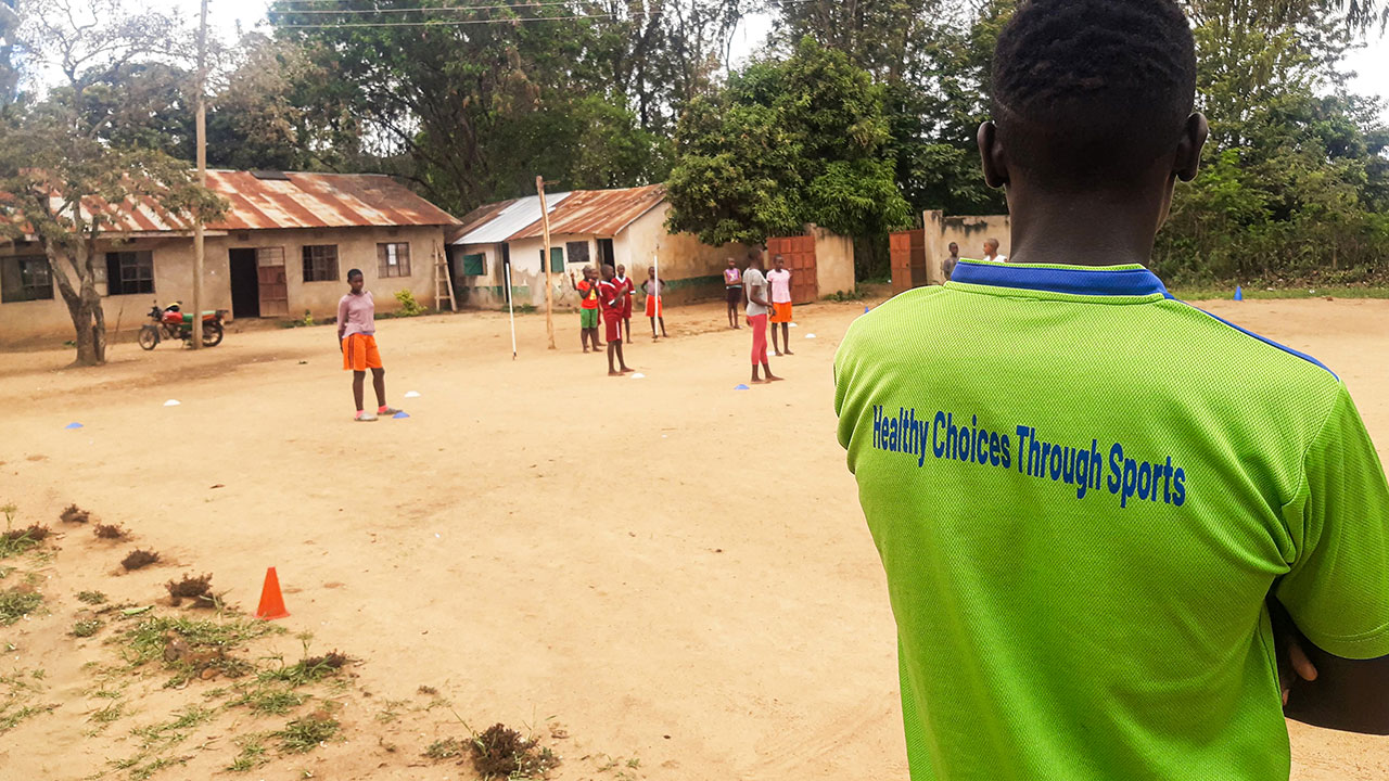 The HESPO project manager stands on the edge of a sandy pitch in his village in Kenya and watches his team's handball players.